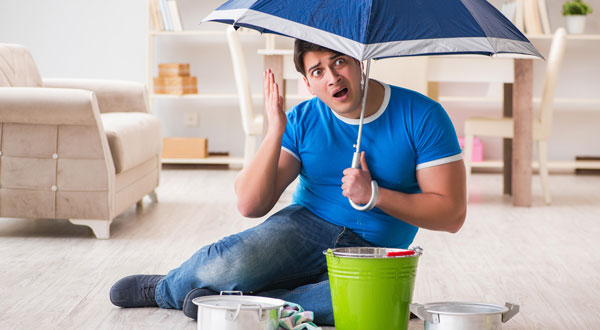 man in wet basement with umbrella